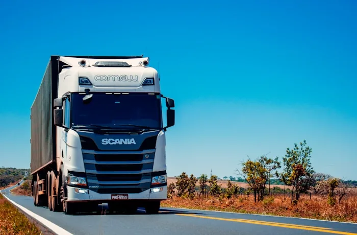 White Scania semi-truck on a highway under a clear blue sky