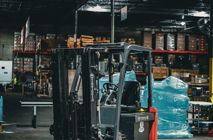 Forklift beside blue-wrapped pallets in an organised warehouse dispatch area