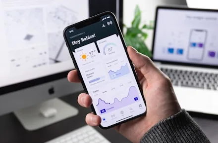 Hand holding a smartphone with a native-quality dashboard interface