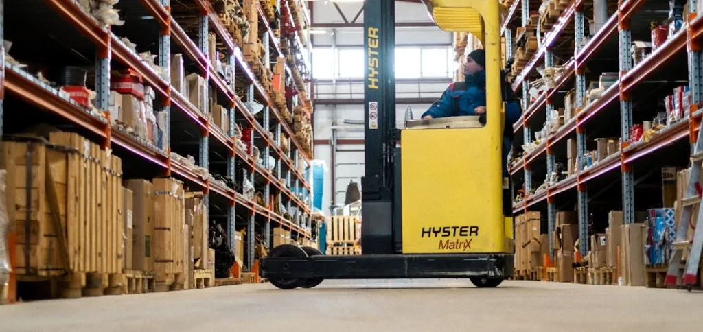 Yellow Hyster reach truck operating in a narrow warehouse aisle